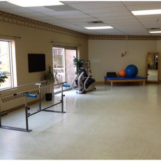 A spacious rehabilitation room equipped with exercise bars, fitness balls, and other workout equipment.