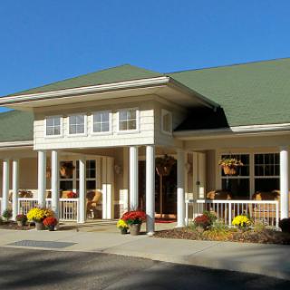 A charming residential building with a welcoming front porch and colorful flowers in the landscape.