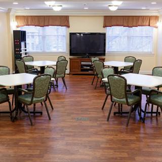 A neatly arranged meeting room with tables, chairs, and a television.