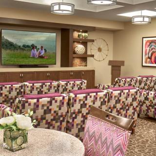 A modern conference room with patterned chairs, a large screen, and diverse artwork.