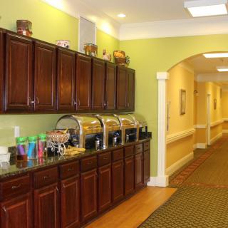 A buffet setup with various food containers and drinks in a well-lit hallway.