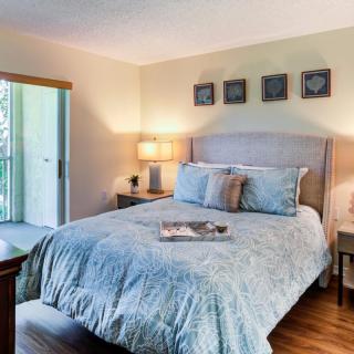 A cozy bedroom decorated with a light blue comforter, bedside lamps, and wall art.