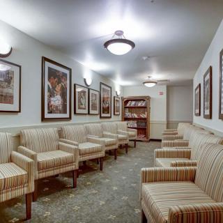 Empty waiting room with striped chairs and framed artwork on the walls.