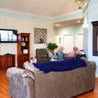 A cozy living room with two people sitting on a sofa, watching television.