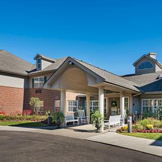 Modern residential building with a landscaped entrance under a clear blue sky.