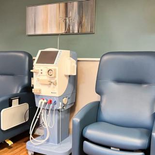 A dialysis machine situated between two comfortable chairs in a healthcare clinic.