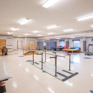 A spacious rehabilitation room equipped with various exercise and therapy tools for patients.