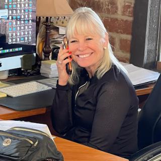 A cheerful woman talking on the phone at her office desk.