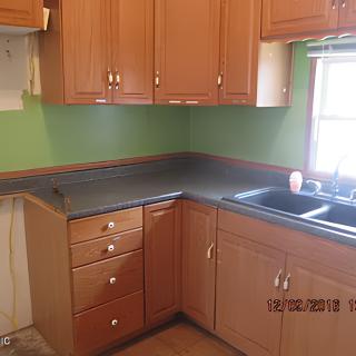 A kitchen with wooden cabinets, a dark countertop, and a green painted wall.