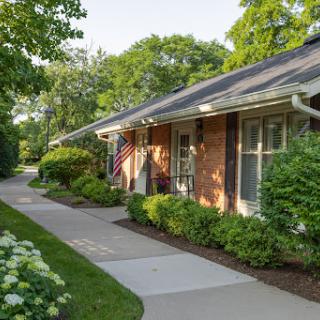 A charming residential area featuring a well-maintained house with a walkway surrounded by lush greenery.