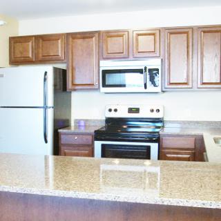 A modern kitchen featuring a combination of brown cabinetry and white appliances.