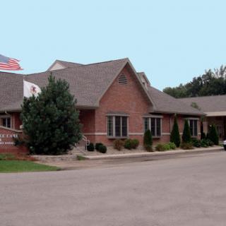 A brick commercial building with landscaped surroundings and an American flag.