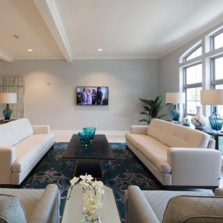 A modern living room with neutral-toned sofas, a large coffee table, and a wall-mounted television.