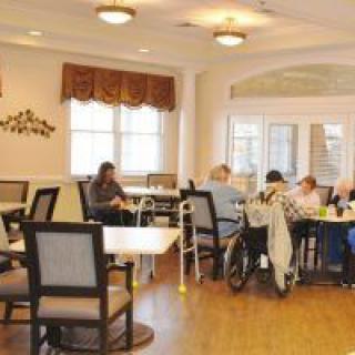 A cozy dining area in a nursing home where residents are gathered around tables.