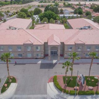 An aerial view of a large building complex with palm trees and a parking lot.