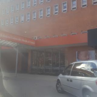 A view of an urban building with a vehicle parked nearby.