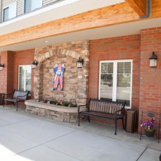 A charming exterior view featuring stone accents, benches for relaxation, and decorative artwork.