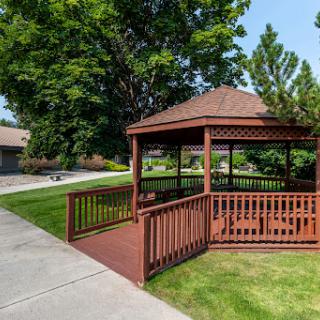 A charming wooden gazebo surrounded by lush greenery in a serene outdoor setting.