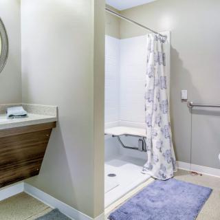 A modern, accessible bathroom with a shower featuring a grab bar and curtain.