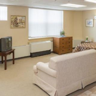 A cozy living room with a sofa, television, and dresser near a window.