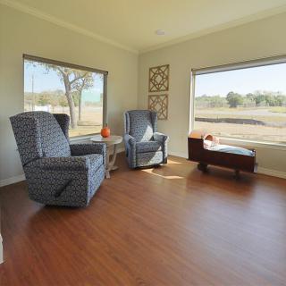 A cozy living room with armchairs and large windows overlooking a scenic outdoor view.
