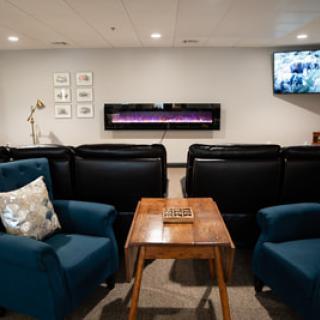 A cozy living room with comfortable seating and a wall-mounted fireplace.