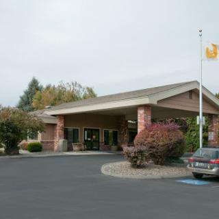 A welcoming entrance to a commercial building, featuring landscaped surroundings and a flag.