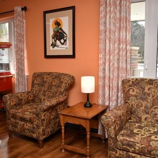 Cozy living room with patterned armchairs and warm orange walls.