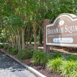 Entrance sign for Savannah Square, surrounded by trees and greenery.