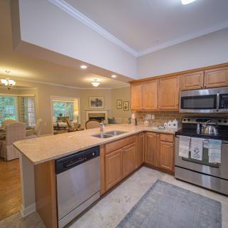 A modern kitchen with wood cabinets and stainless steel appliances in an open-concept layout.