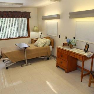 A neatly arranged hospital room with a bed, side table, and window.