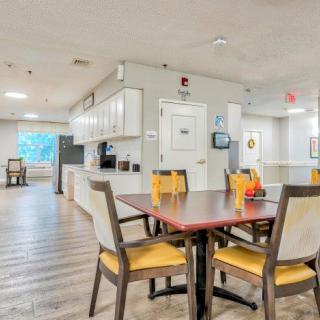 A cozy dining area with wooden floors and a kitchen in the background.