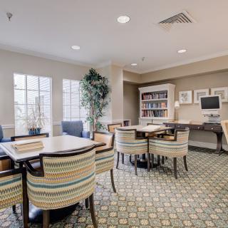 A well-lit study room with comfortable seating, bookshelves, and a computer workstation.