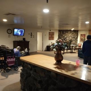 A cozy living room with a television and people relaxing, including one person in a wheelchair.