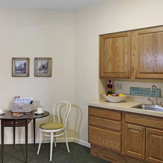 A small kitchen area with wooden cabinets, a sink, and a table with two chairs.