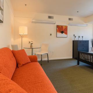 A modern living room featuring an orange sofa, a stylish lamp, and contemporary artwork.