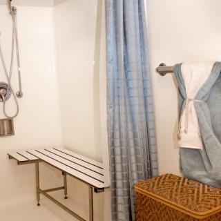 An accessible bathroom with a shower bench and blue curtain.
