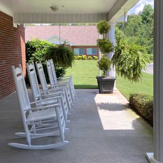 A peaceful porch with white rocking chairs and lush green plants.