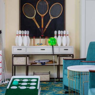 A stylish game room with retro decor featuring vintage tennis rackets and bowling pins.
