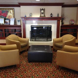 A cozy seating area featuring two chairs and an ottoman arranged around a fireplace.