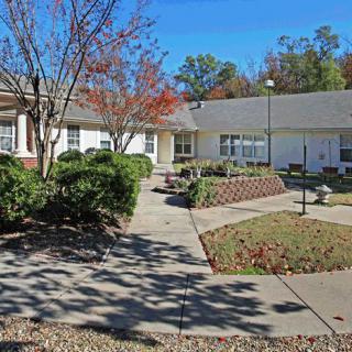 A residential building surrounded by a landscaped garden with walkways and trees.