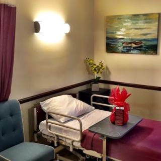 A cozy patient room featuring a hospital bed, a comfortable chair, and decorative elements.