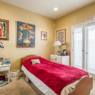 A cozy bedroom with a single bed and colorful artwork on the walls.