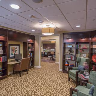 A cozy library interior with bookshelves, seating, and a computer station.