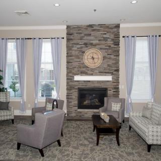 A modern living room with a stone fireplace, comfortable seating, and neutral decor.