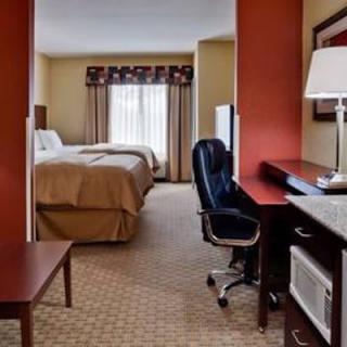A well-furnished hotel room featuring a bed, desk, chair, and television.