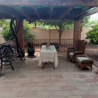 A serene patio setup with comfortable seating and a table, surrounded by greenery.