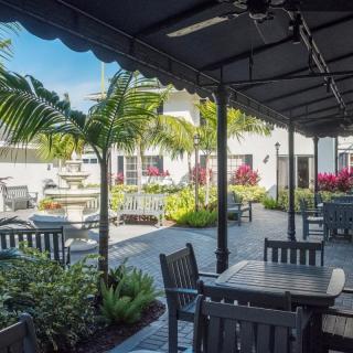 A sunny outdoor patio area with tables, chairs, and lush greenery.
