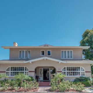 A classic two-story house with a well-maintained front yard under a clear blue sky.