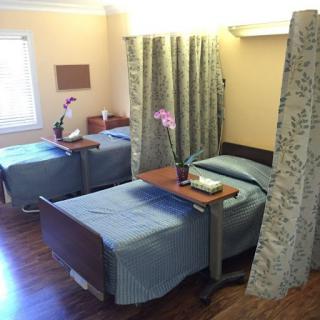 A neatly arranged hospital patient room with two beds separated by curtains.